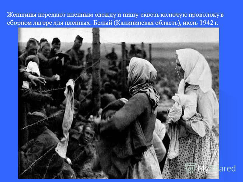 Женщины передают пленным одежду и пищу сквозь колючую проволоку в сборном лагере для пленных. Белый (Калининская область), июль 1942 г.